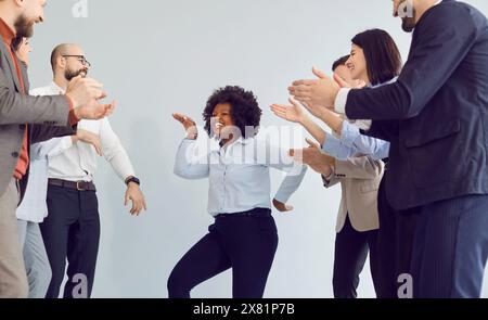 Il team multinazionale degli uffici celebra il successo, la danza e l'applauso in ufficio Foto Stock