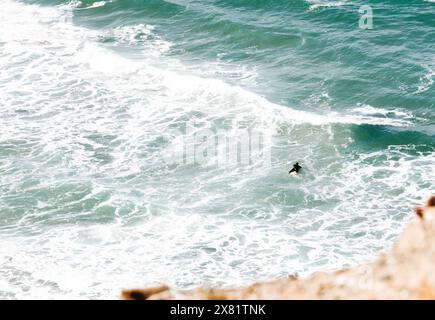 Un surfista steso su una tavola da surf in attesa di un'onda adatta da solo nell'oceano. vista dall'alto. Concetto di vibrazione minima per surfisti Foto Stock