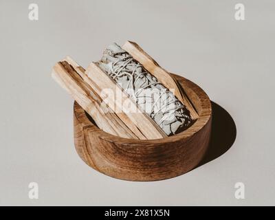 Salvia bianca e palo Santo si attaccano in una scatola di legno su sfondo chiaro. Una serie di incenso per fumigazione. Vista frontale. Foto Stock