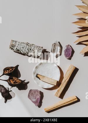 Salvia bianca, Palo Santo e cristalli di ametista e quarzo su sfondo beige chiaro. Vista dall'alto. Una serie di incenso per fumigazione. Foto Stock