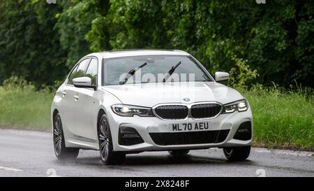 Stony Stratford, Regno Unito - 22 maggio 2024: 2020 BMW 330 ibrida elettrica bianca che guida su una strada britannica in una giornata di pioggia Foto Stock