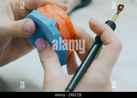 L'odontotecnico crea una base di cera e aggiunge cera per formare lo stampo. Concetto odontoiatrico Foto Stock