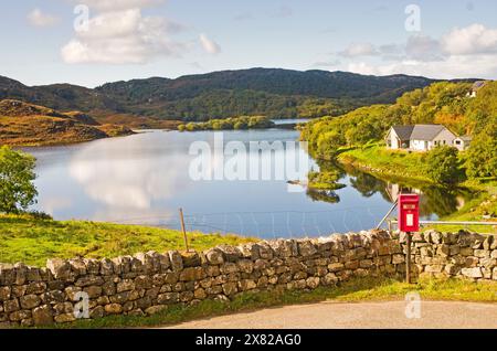 La cassetta postale del villaggio a Drumbeg. Un piccolo insediamento sulla costa di Assynt sulla rotta NC 500, con il pittoresco Loch Drumbeg subito dietro. Scozia Foto Stock