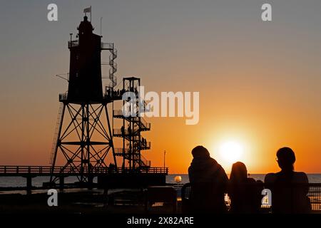 Tramonto, faro Obereversand, sagome, persone, Mare del Nord, Dorum-Neufeld, Wurster Land, bassa Sassonia, Germania Foto Stock