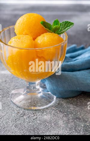 Cucchiaio di sorbetto al mango nel recipiente di vetro Foto Stock