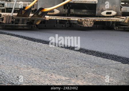 Riparazione della superficie stradale asfaltata - vecchio strato rimosso e rivestimento di un autocarro per pavimentazioni industriale che posa nuovo asfalto sul cantiere. Foto Stock
