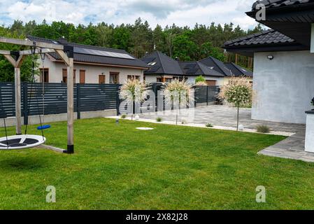 Una moderna recinzione a pannelli in colore antracite, un parco giochi visibile a forma di cubo Foto Stock