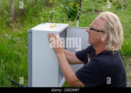 Montaggio di un sistema automatico di alimentazione dell'acqua per l'irrigazione a goccia. Un uomo installa una scatola di assemblaggio. Foto Stock