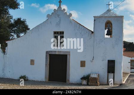 La chiesa del villaggio del XVIII secolo di Bordeira, Algarve, Portogallo, con pareti bianche e una piccola torre dell'orologio Foto Stock