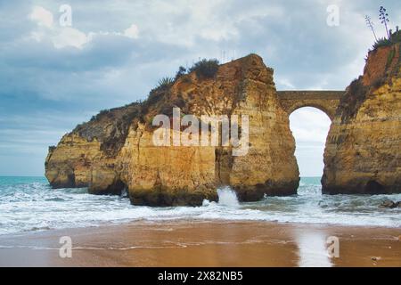 Antico ponte di pietra che collega la terraferma a una piccola isola rocciosa, Lagos, Portogallo, Algarve. Sembra un'immagine di un film fantasy. Foto Stock