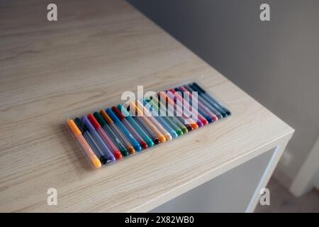 Una confezione di pennarelli colorati su un tavolo in legno, luce che entra dalla finestra Foto Stock