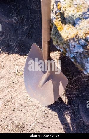 una pala sostenuta su una roccia in uno scavo archeologico Foto Stock