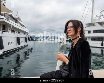 La giovane donna con un abito elegante si pone elegantemente vicino a yacht ormeggiati. Francia Foto Stock