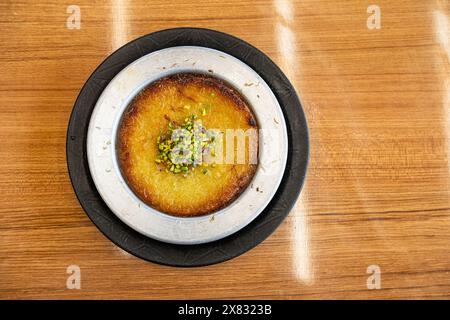 Delizioso kunefe turco tradizionale con pistacchio sopra. Servito caldo e con sciroppo. Künefe turco, dessert sud-orientale caldo e formaggio. Foto Stock