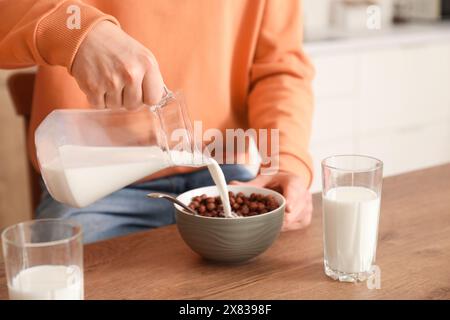 Un figlio piccolo che mangia fiocchi di mais con latte a colazione in cucina, primo piano Foto Stock