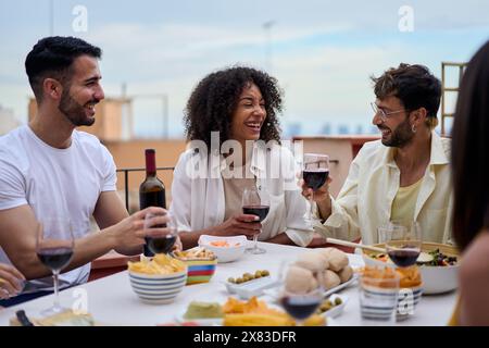 Un gruppo di giovani e allegri amici riuniti a pranzo. Persone millenarie sedute a tavola Foto Stock