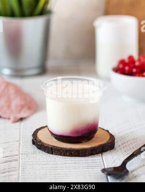 panna cotta o yogurt greco con marmellata di bacche in una tazza di plastica trasparente Foto Stock