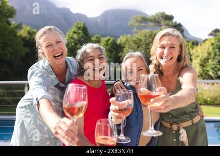 Diverse amiche anziane che tengono in mano bicchieri da vino e ridono all'aperto Foto Stock