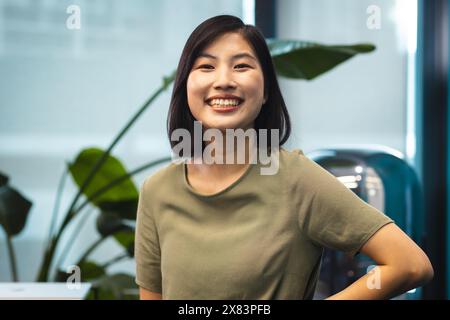 Nel moderno ufficio per affari, giovane donna asiatica con capelli neri corti sorridenti Foto Stock