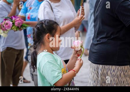 Bangkok, Thailandia. 22 maggio 2024. Un ragazzino ha visto tenere in mano un fiore di loto nel giorno di Visakha Bucha, al Tempio di Lat Phrao, situato in una comunità a basso reddito, a Bangkok, Thailandia. Visakha Bucha, una delle più importanti festività buddiste della Thailandia, commemora la nascita, l'illuminazione e il passaggio del Buddha Gautama, tutti nella stessa data. I buddisti thailandesi visitano in genere i templi per fare il merito, che comporta attività come dare l'elemosina ai monaci, ascoltare sermoni e partecipare a vari rituali religiosi. (Foto di Nathalie Jamois/SOPA Images/Sipa USA) credito: SIPA USA/Alamy Live News Foto Stock