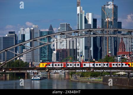 Principale con ferrovia regionale sulla Deutschherrnbruecke e una nave da carico di fronte allo skyline di Francoforte sul meno, Assia, Germania Foto Stock