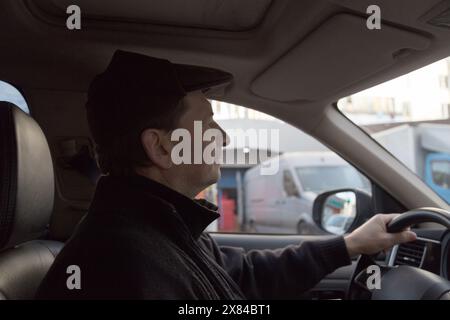 Un uomo guida un'auto per la città. Vista dall'interno della vettura. Primo piano. Foto Stock