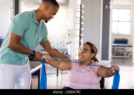 Una paziente paraplegica birazziale e fisioterapista maschile che lavora con bande Foto Stock