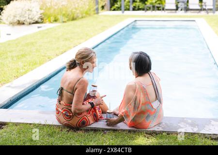 All'aperto, diverse amiche anziane che tengono bevande a bordo piscina, spazio fotocopie Foto Stock