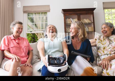 Diverse amiche anziane che ridono insieme sul divano a casa Foto Stock