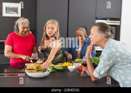 Diverse amiche anziane preparano l'insalata a casa Foto Stock