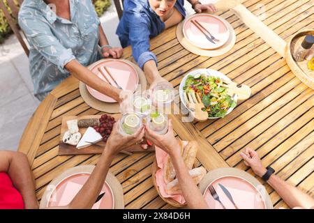 Diverse amiche anziane brindano all'aperto durante un pasto Foto Stock