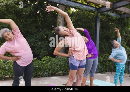 Diverse amiche senior che si allungano, indossano abbigliamento casual per il fitness e fanno yoga Foto Stock