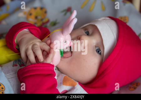 Nella culla il bambino gioca con un giocattolo morbido Foto Stock