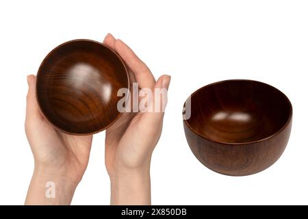 La mano femminile tiene una ciotola di legno isolata su uno sfondo bianco. Foto Stock