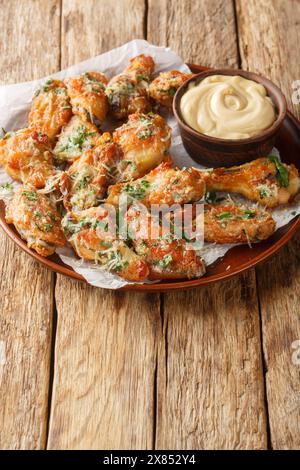 Le ali di parmigiano di pollo sono cotte al forno o fritte ad aria e poi ricoperte in una salsa di parmigiano all'aglio al bufala sul piatto del tavolo. Verticale Foto Stock