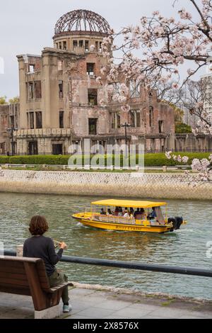 Crociera sul fiume Hiroshima passando davanti alla Cupola Genbaku (Cupola della bomba atomica) e al Parco Memoriale della Pace di Hiroshima. I ciliegi fioriscono in piena fioritura in Giappone. Foto Stock