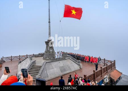 Picco del monte Fansipan, città di sa Pa, provincia di Lao Cai, Vietnam - 20 febbraio 2024: Guarda la cerimonia nazionale di innalzamento della bandiera sulla vetta del monte Fansipan Foto Stock