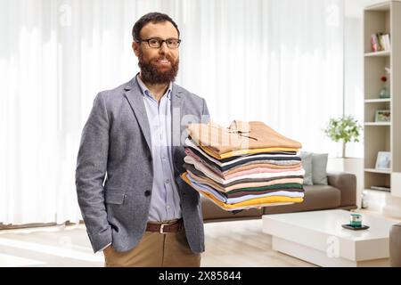 Uomo con un mucchio di vestiti piegati a casa in salotto Foto Stock