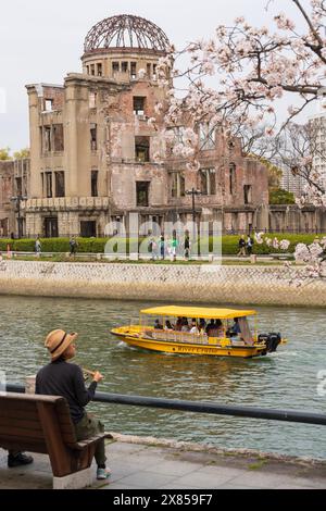 Crociera sul fiume Hiroshima passando davanti alla Cupola Genbaku (Cupola della bomba atomica) e al Parco Memoriale della Pace di Hiroshima. I ciliegi fioriscono in piena fioritura in Giappone. Foto Stock