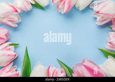 I tulipani dai colori pastello impreziosiscono il tavolo, offrendo uno sfondo sereno e vibrante, perfetto per feste primaverili o semplici gioie Foto Stock