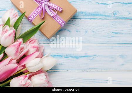 I tulipani dai colori pastello impreziosiscono il tavolo, offrendo uno sfondo sereno e vibrante, perfetto per feste primaverili o semplici gioie Foto Stock