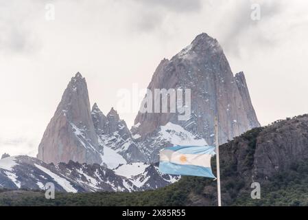 Una bandiera argentina sta sventolando su un palo di fronte a una montagna di Fitz Roy. Foto Stock