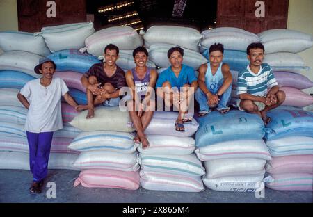 Filippine, Mindanao, i lavoratori siedono su borse riempite di farina di riso in una riseria nella città di Davao. Foto Stock