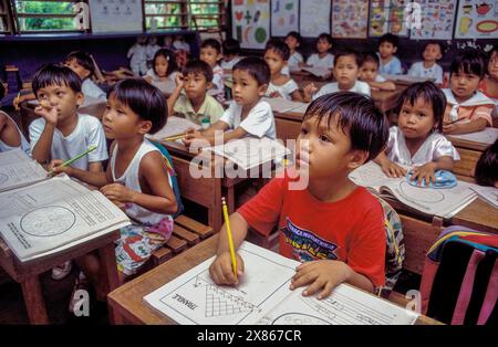 Filippine, Mindanao, Davao; bambini che ascoltano il loro insegnante alla scuola elementare. Foto Stock