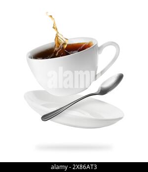 Tazza di caffè, piattino e cucchiaio in aria su sfondo bianco Foto Stock