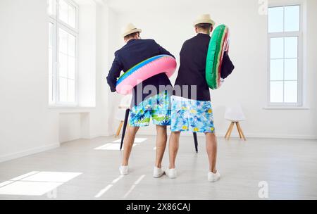 Colleghi divertenti che si divertono a stare in ufficio con anelli di gomma e andare in vacanza d'estate Foto Stock