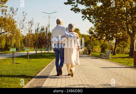 Felice coppia romantica e matura innamorata che si abbraccia insieme mentre cammina per un appuntamento nel parco. Foto Stock