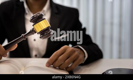 Uomo giudice mano che tiene il martelletto per sbattere su un blocco sonoro nella stanza del tribunale. Primo piano di un avvocato che tiene il martelletto alla scrivania. Uomo che tiene il martelletto di legno nella ha Foto Stock