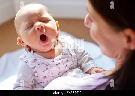 Madre che tiene in braccio un bambino sbadigliante Foto Stock