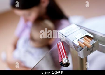 Donna che fuma accanto al neonato Foto Stock